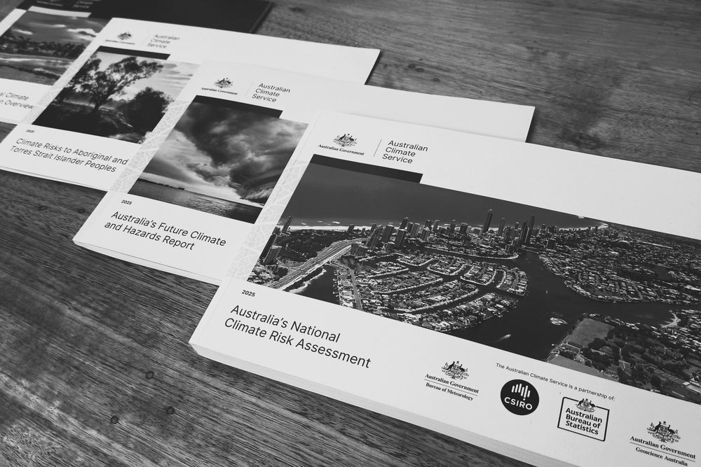 Printed copies of Australia's National Climate Risk Assessment reports on a wooden table
